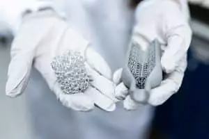 Ce super-conducteur ultra-rapide va révolutionner les batteries avec une puissance jamais vue Laboratory setting showing gloved hands holding innovative 3D printed metal structures.