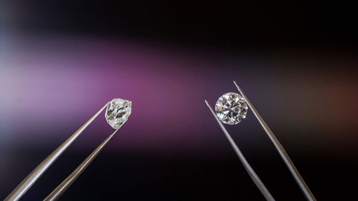 Deux diamants tenus par des pincettes métalliques sur un fond sombre à reflets violets : à gauche un diamant brut irrégulier, à droite un diamant taillé rond.
