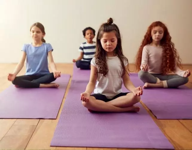 Des enfants assis en tailleur sur des tapis de yoga