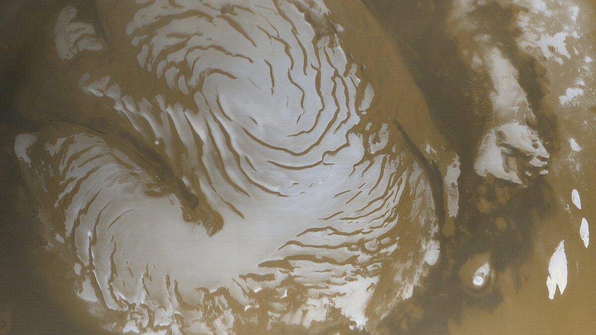 Vue orbitale de la calotte polaire nord de Mars, avec des terrains stratifiés sombres et des zones blanches de glace sur une surface ocre.
