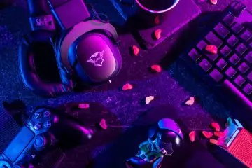 Colorful flat lay of gaming gear including headset, controller, and keyboard under vibrant lighting.