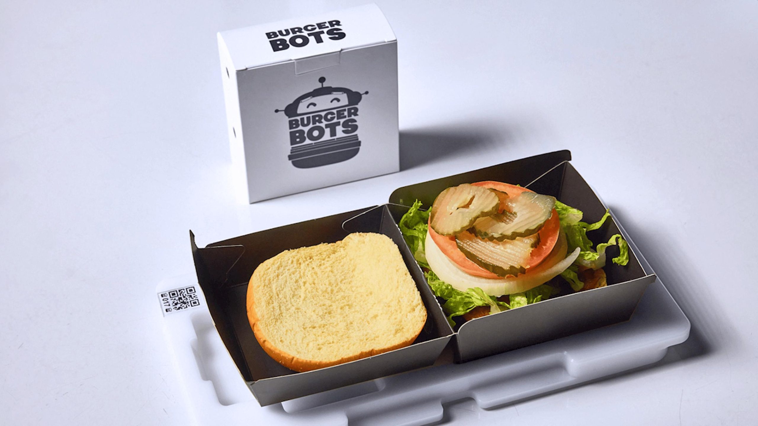 Assemblage final par BurgerBots : un burger à 18 $, toujours sur son plateau avec code QR
