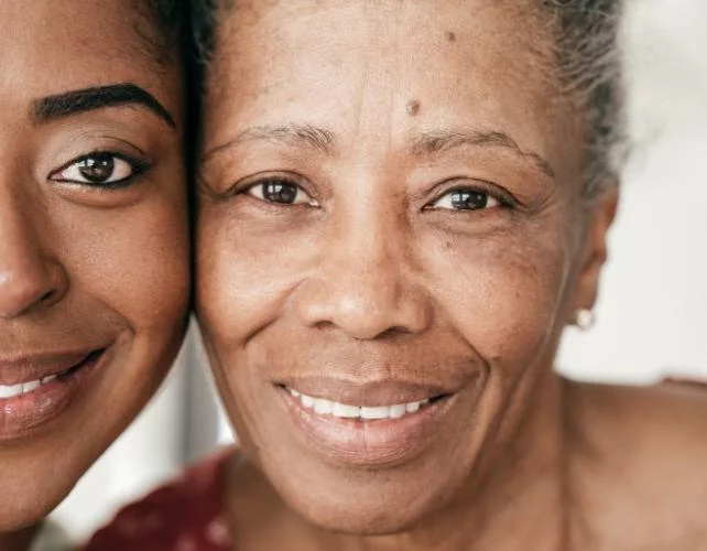 Visage d'une jeune femme à côté de celui d'une femme plus âgée, toutes deux souriantes