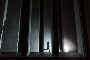 Dynamic silhouette of a person running through an urban setting with dramatic lighting.
