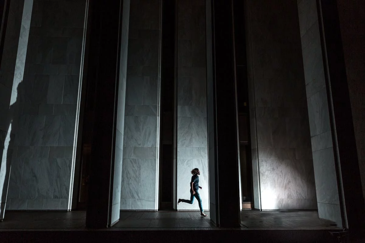 Dynamic silhouette of a person running through an urban setting with dramatic lighting.