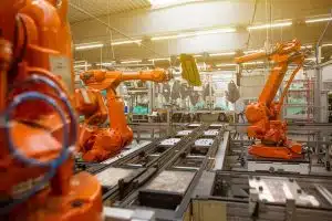 5 raisons pour lesquelles la robotique industrielle améliore la fiabilité dans des conditions difficiles a factory filled with lots of orange machines