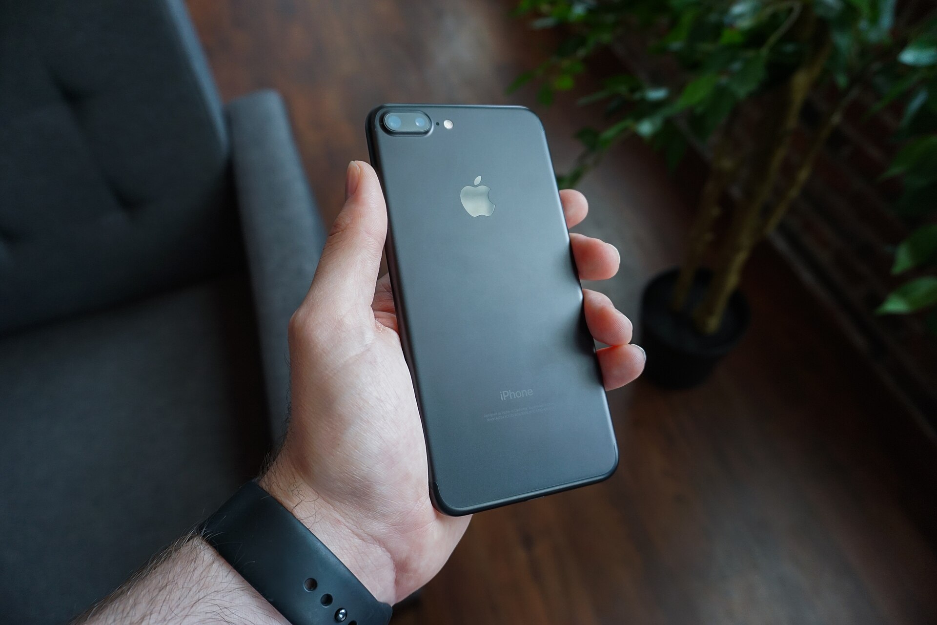 Main qui tient un smartphone noir vu de dos